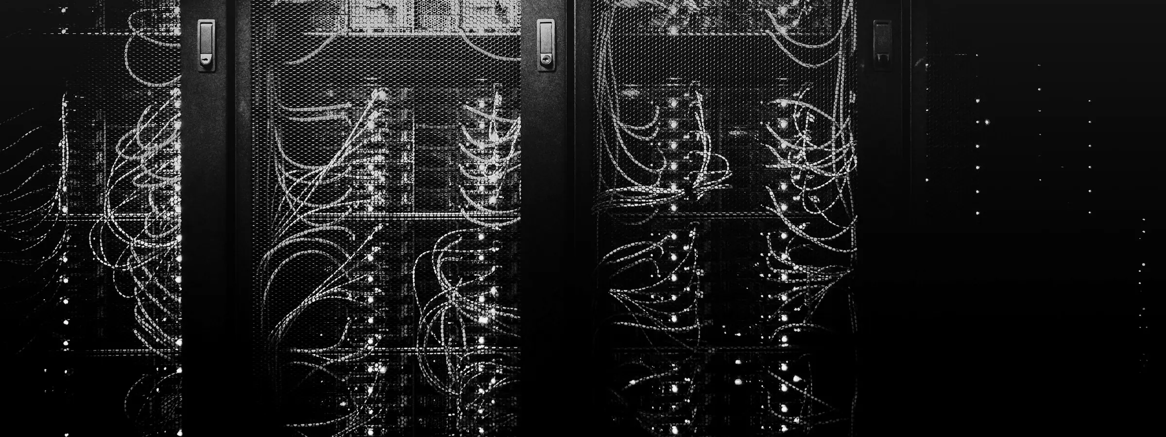 Rows of server racks lit dimly in a data center aisle